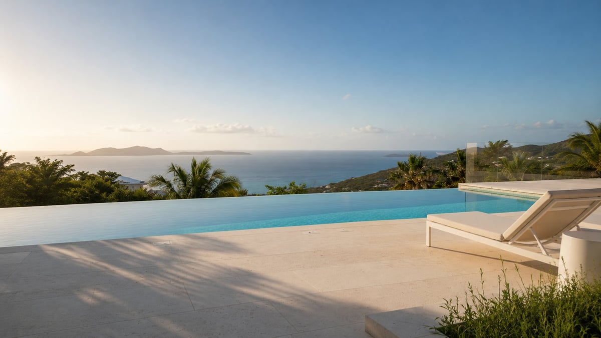 Modern infinity pool overlooking tropical coastline with ocean view and palm trees at sunset